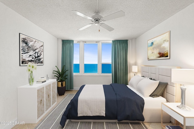 2987 S Atlantic Ave Unit 903, Daytona Beach Shores, FL 32118 - bedroom featuring a water view, a textured ceiling, and a ceiling fan