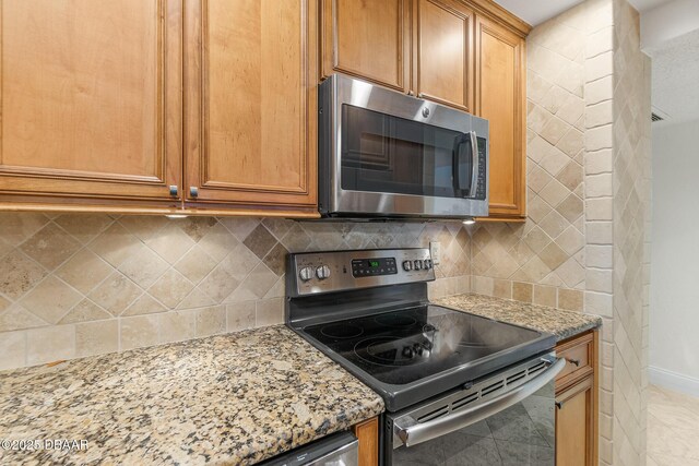 2987 S Atlantic Ave Unit 903, Daytona Beach Shores, FL 32118 - kitchen featuring stainless steel appliances, light stone countertops, baseboards, backsplash, and brown cabinets