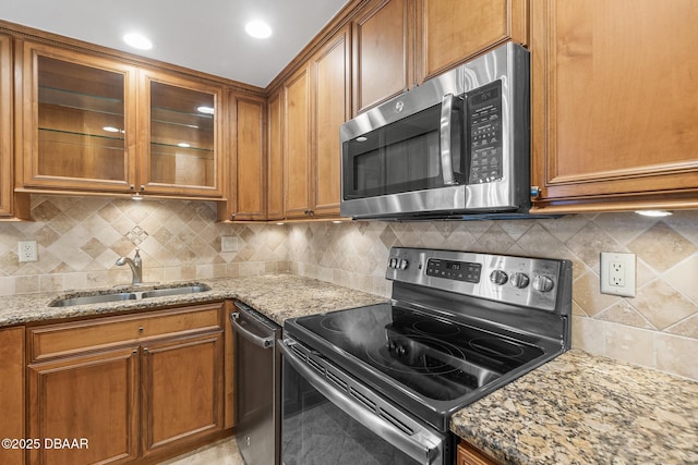 2987 S Atlantic Ave Unit 903, Daytona Beach Shores, FL 32118 - kitchen featuring appliances with stainless steel finishes, a sink, brown cabinetry, and light stone counters