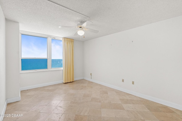 2987 S Atlantic Ave Unit 903, Daytona Beach Shores, FL 32118 - unfurnished room featuring ceiling fan, baseboards, a textured ceiling, and a water view