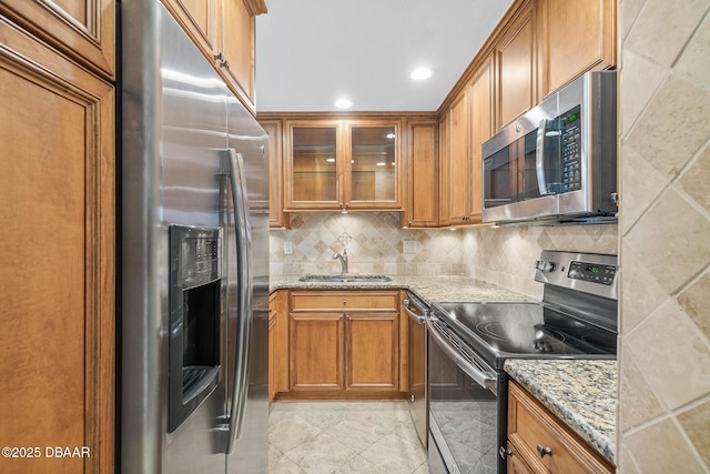 2987 S Atlantic Ave Unit 903, Daytona Beach Shores, FL 32118 - kitchen featuring appliances with stainless steel finishes, a sink, brown cabinetry, light stone countertops, and recessed lighting