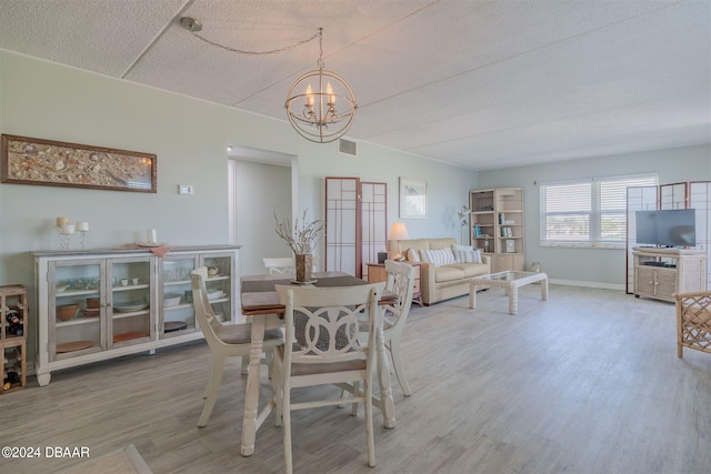 dining area with hardwood / wood-style floors, a notable chandelier, and a textured ceiling