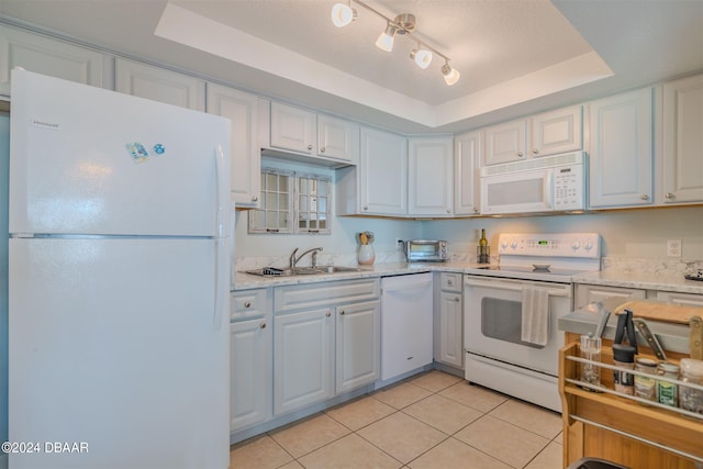 kitchen featuring sink, light tile patterned floors, a tray ceiling, white appliances, and white cabinets