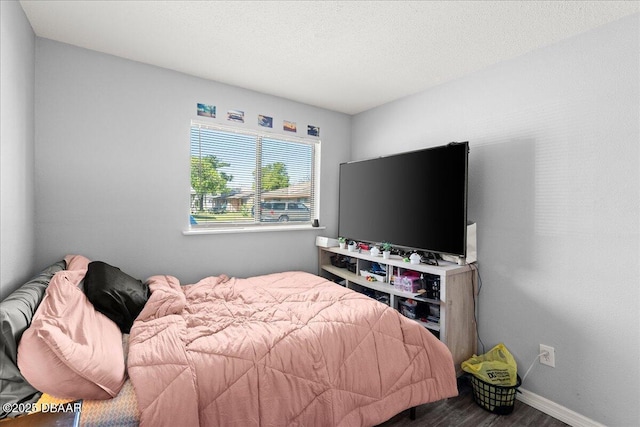 bedroom featuring a textured ceiling, wood finished floors, and baseboards