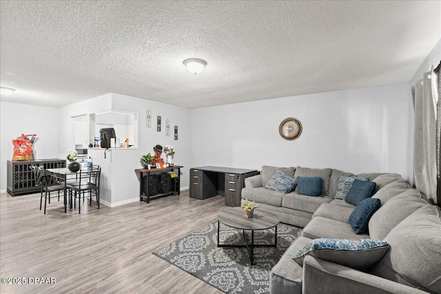 living area with baseboards, a textured ceiling, and light wood finished floors