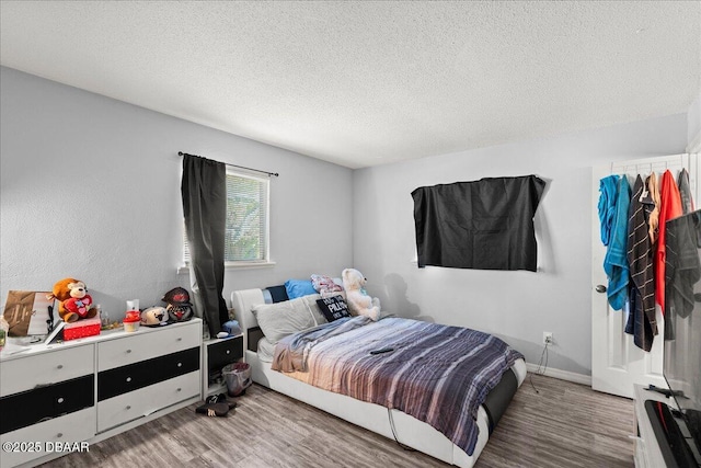 bedroom with a textured ceiling, wood finished floors, and baseboards