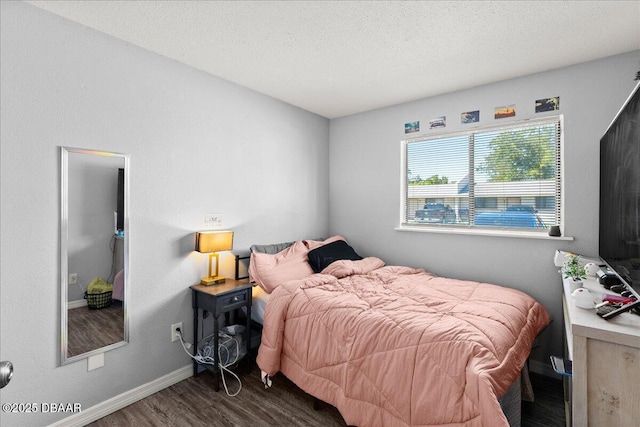 bedroom with a textured ceiling, wood finished floors, and baseboards