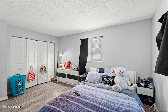 bedroom with a closet, a textured ceiling, and wood finished floors