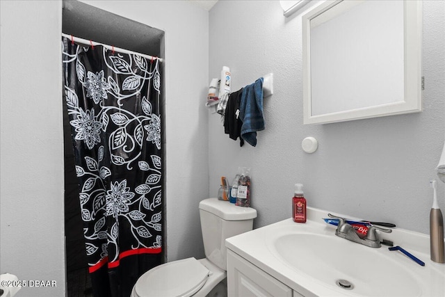 full bathroom featuring a textured wall, a shower with shower curtain, vanity, and toilet