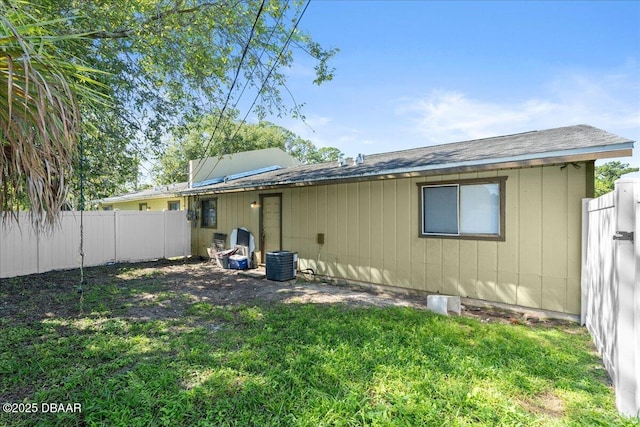 rear view of property with a fenced backyard, cooling unit, and a yard