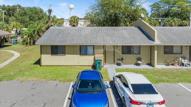 single story home with a front yard, a patio area, and roof with shingles