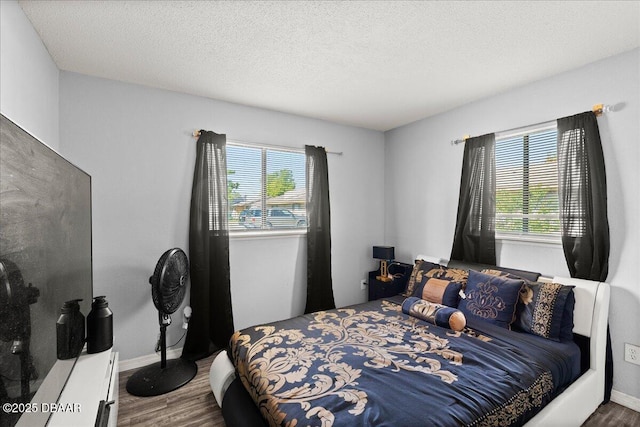 bedroom with a textured ceiling, multiple windows, and wood finished floors