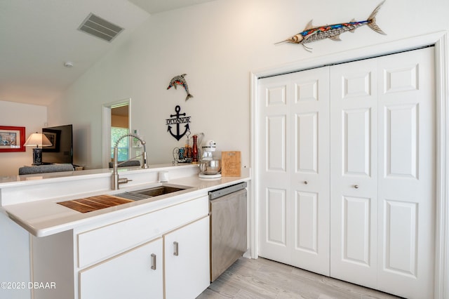 49 Felshire Ln, Palm Coast, FL 32137 - kitchen with stainless steel dishwasher, vaulted ceiling, a peninsula, light countertops, and white cabinetry