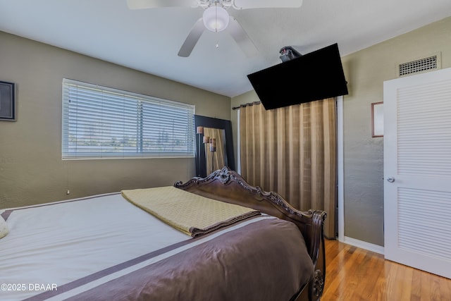 bedroom featuring baseboards, wood finished floors, visible vents, and a ceiling fan