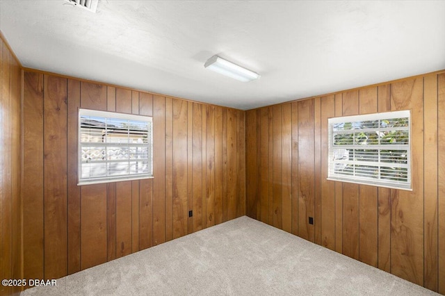 unfurnished room featuring carpet floors and wood walls