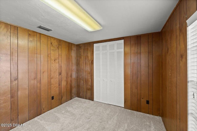 unfurnished bedroom featuring carpet floors, a closet, and wood walls