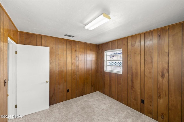 carpeted empty room featuring wooden walls