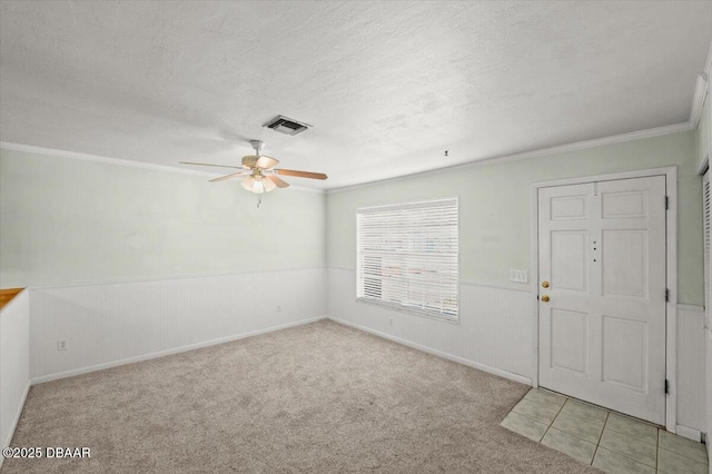 foyer entrance featuring ceiling fan, crown molding, light colored carpet, and a textured ceiling