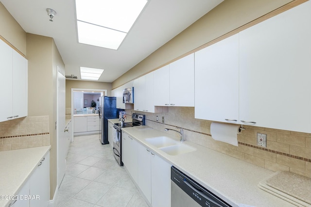 kitchen with a sink, stainless steel appliances, light countertops, white cabinetry, and tasteful backsplash