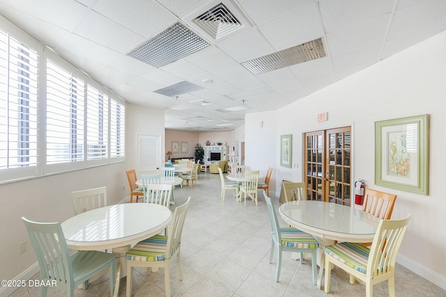 dining room with light tile patterned flooring, a paneled ceiling, visible vents, and baseboards