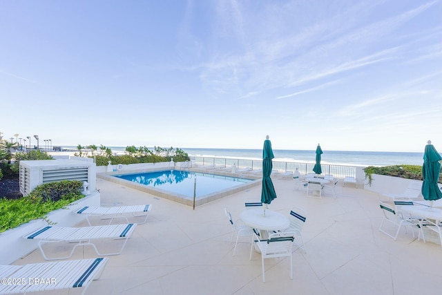 pool with outdoor dining space, a patio, and a water view