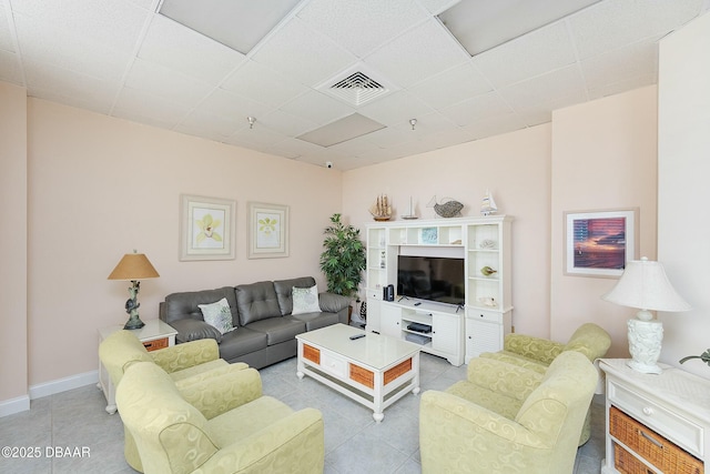 living room with light tile patterned floors, visible vents, baseboards, and a drop ceiling