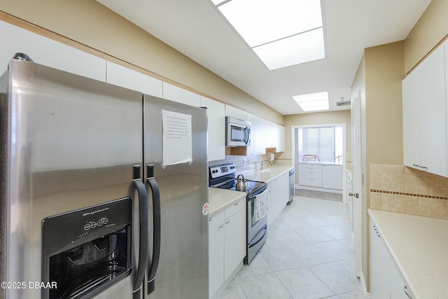 kitchen with light tile patterned floors, stainless steel appliances, tasteful backsplash, and light countertops