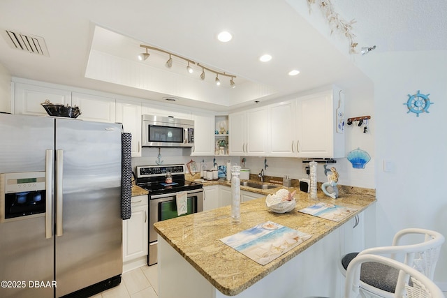 kitchen with a tray ceiling, a peninsula, visible vents, and appliances with stainless steel finishes