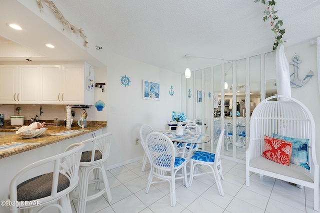 dining space featuring light tile patterned flooring, recessed lighting, a textured ceiling, and baseboards