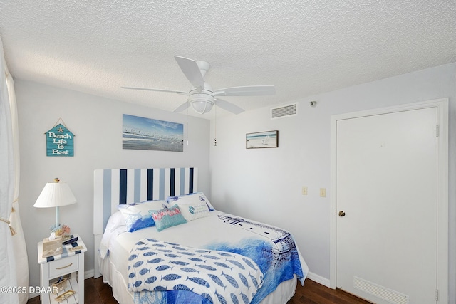 bedroom with ceiling fan, visible vents, a textured ceiling, and dark wood finished floors