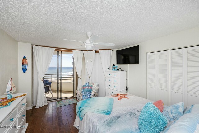 bedroom with a ceiling fan, dark wood-type flooring, a closet, a textured ceiling, and access to outside