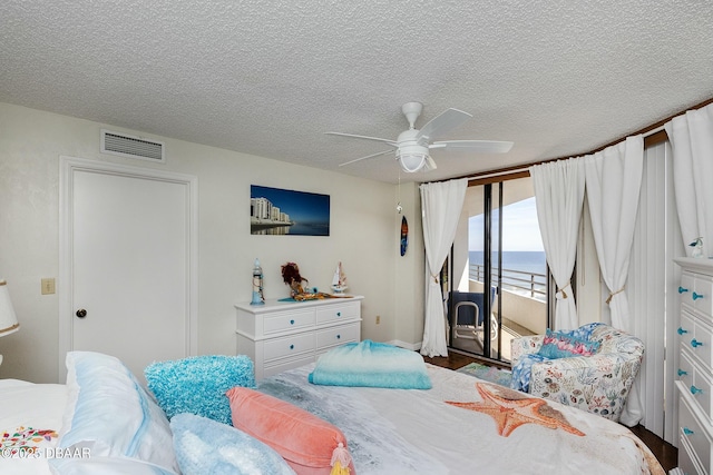 bedroom with access to exterior, visible vents, a textured ceiling, and a ceiling fan