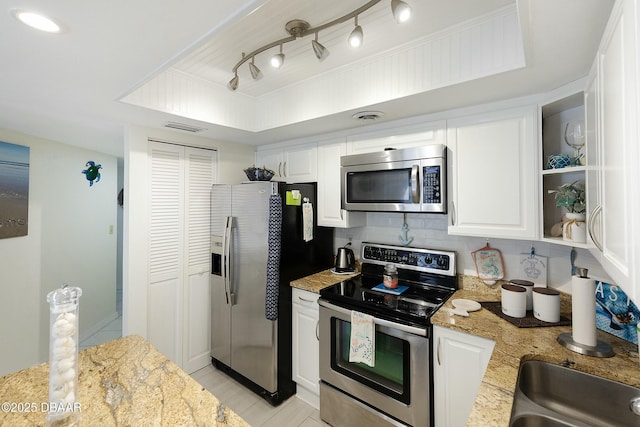 kitchen with visible vents, appliances with stainless steel finishes, white cabinets, a raised ceiling, and light stone countertops