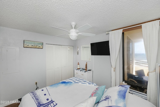 bedroom with electric panel, a textured ceiling, a closet, and a ceiling fan