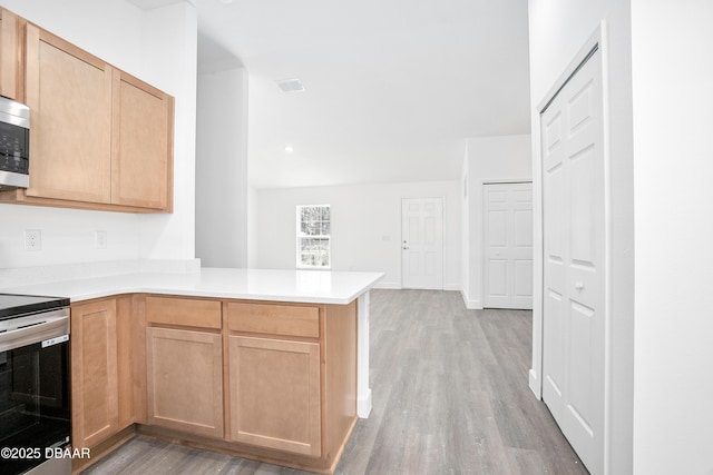 kitchen with kitchen peninsula, light brown cabinets, light wood-type flooring, and stainless steel range with electric cooktop