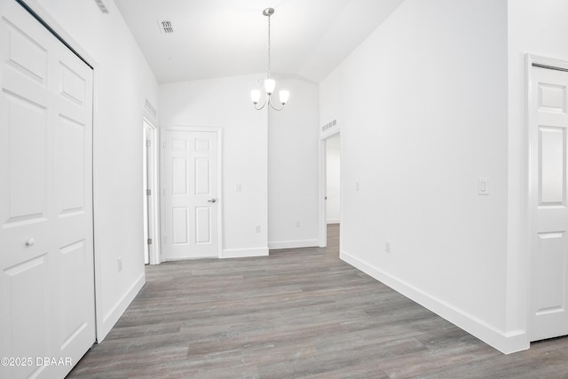 unfurnished dining area featuring hardwood / wood-style flooring, vaulted ceiling, and an inviting chandelier