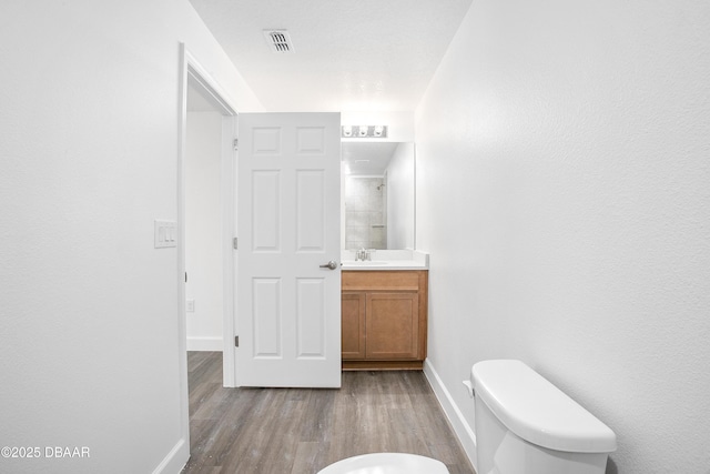 bathroom with wood-type flooring, vanity, and toilet