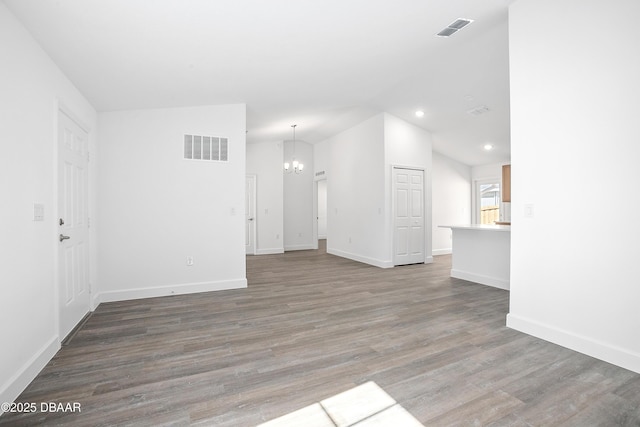 unfurnished living room featuring high vaulted ceiling, wood-type flooring, and an inviting chandelier