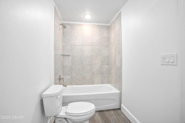 bathroom with hardwood / wood-style flooring, toilet, and tiled shower / bath