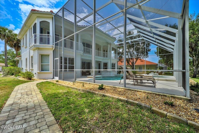 rear view of property with a balcony, a patio, and glass enclosure