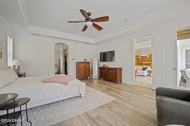 bedroom with ceiling fan, ornamental molding, a raised ceiling, and light wood-type flooring