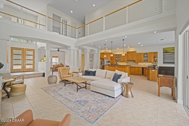 living room featuring light tile patterned flooring, a high ceiling, french doors, and ornate columns