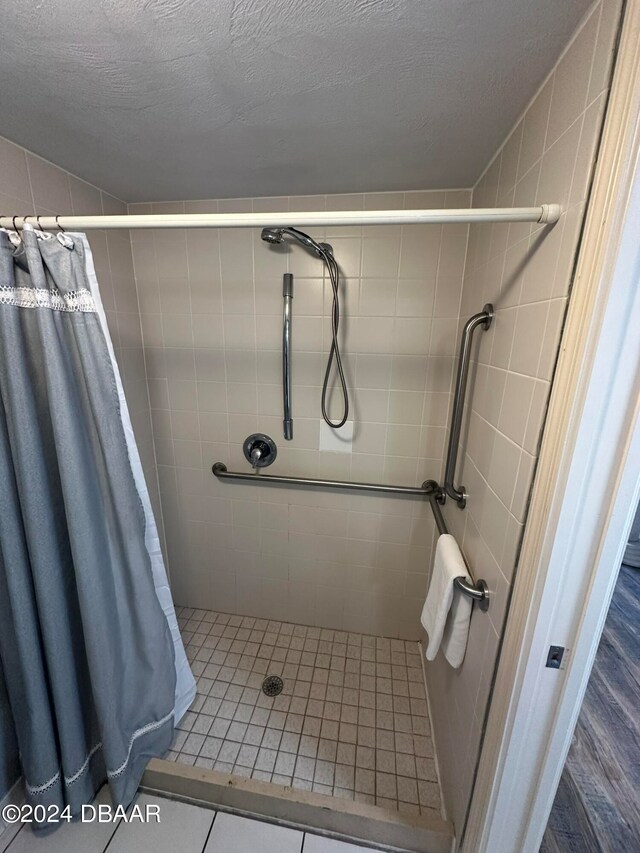 bathroom with walk in shower, a textured ceiling, and tile patterned flooring