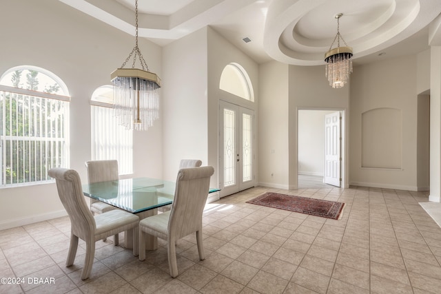 dining area with a raised ceiling, french doors, a notable chandelier, and plenty of natural light