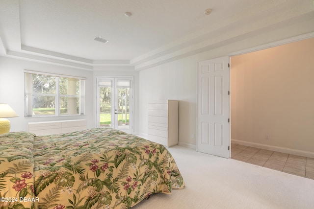 bedroom with light colored carpet, access to exterior, and a tray ceiling