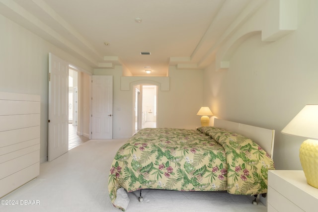 bedroom featuring connected bathroom and light carpet