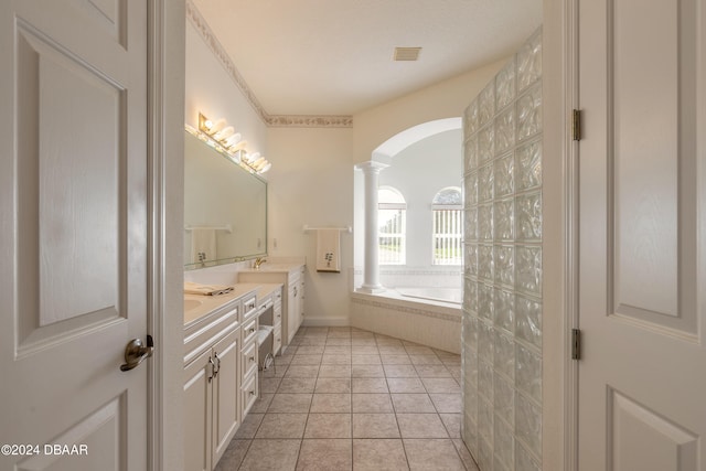 bathroom with a relaxing tiled tub, vanity, tile patterned floors, and decorative columns