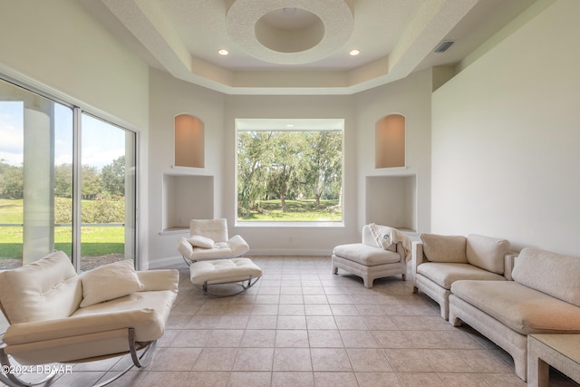 living room featuring light tile patterned flooring, built in features, a textured ceiling, and a tray ceiling