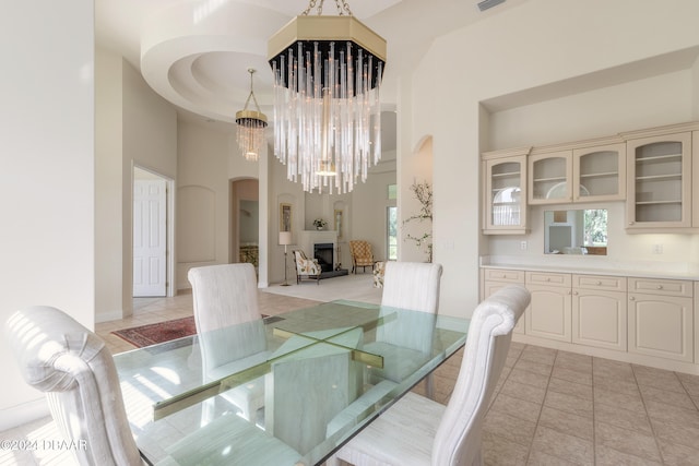 dining space with a towering ceiling, a notable chandelier, and light tile patterned floors