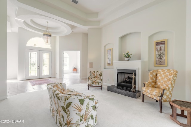 tiled living room with french doors, a towering ceiling, and a raised ceiling